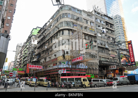 Minibuses turning a corner with hotel, 7 eleven shop and McDonald's below multi-storey flats, Argyle Street, Mong Kok, Hong Kong Stock Photo