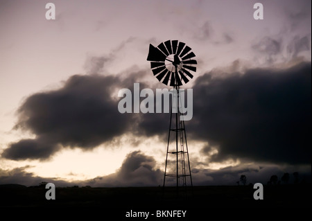 Windmill silhouetted against clouds Stock Photo