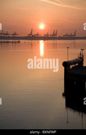 Sunrise over cranes of Port of Felixstowe, Suffolk, England viewed from Harwich, Stock Photo