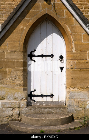 A white church door with black metal strap hinges at Glympton in West Oxfordshire. Stock Photo