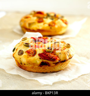 Focaccia bread with olives and sun-dried tomatoes. Nearby are linen and ...