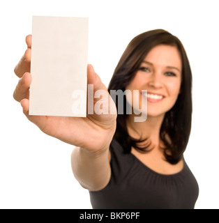 A brunette woman holds a vertical blank business card at arm's length. Focus is on the card, with face out of focus. Stock Photo