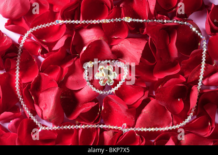 Shiny jewelry over bed or red rose petals Stock Photo