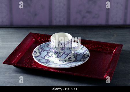 Tea cup victorian style on red indian tray, purple wallpaper background Stock Photo