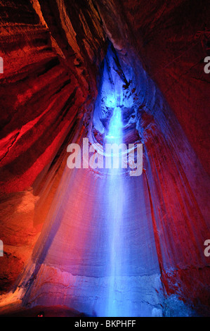 Ruby Falls Underground Waterfall Chattanooga Tennessee | CHATTANOOGA, Tennessee — Blue floodlight rakes down the face of Ruby Falls inside its limestone chamber on Lookout Mountain, the red-lit cave walls framing the cascade in contrasting color. The waterfall drops roughly 145 feet (44 m) from a ceiling crevice deep within the mountain, a formation reached only by elevator and cave passage since its 1928 discovery. Stock Photo