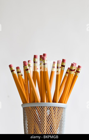 Numerous orange HB lead pencils in holder on white background. Stock Photo