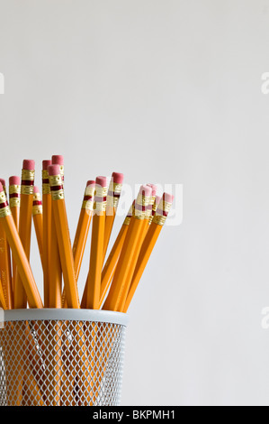 Numerous orange HB lead pencils in holder, on white background. Stock Photo