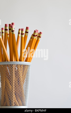 Numerous orange HB lead pencils in holder, on white background. Stock Photo