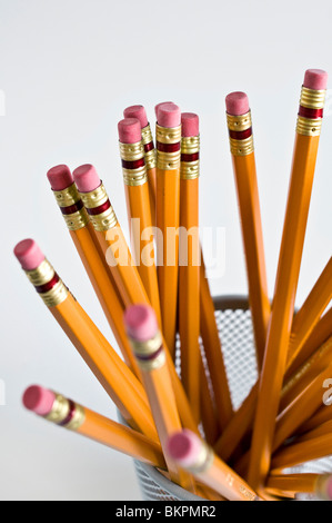 Numerous orange HB lead pencils in holder, on white background. Stock Photo