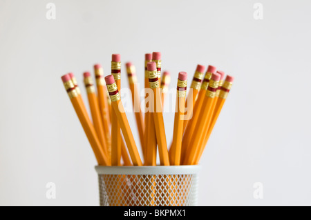 Numerous orange HB lead pencils in holder, on white background. Stock Photo