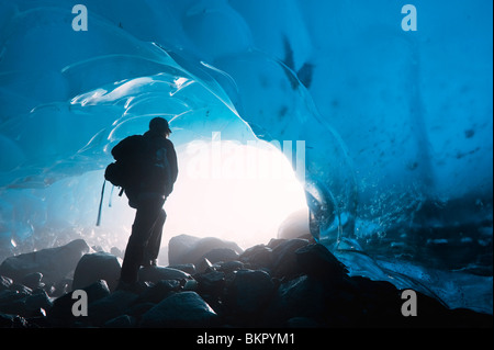 A hiker looks out the entrance of an ice cave in the Mendenhall Glacier, Juneau, Southeast Alaska, Summer Stock Photo