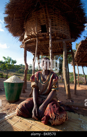 Malawi, Lilongwe, Ntchisi Forest Reserve. In the shade a young woman prepares millet flour for her family. Stock Photo