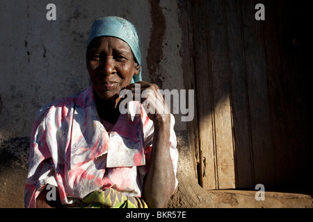 Malawi, Lilongwe, Ntchisi Forest Reserve. An old woman sits by the entrance to her hut in a mountain village. Stock Photo