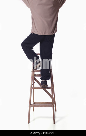 Rear view of man on ladder reaching up. Isolated. Stock Photo