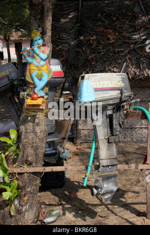 lord krishna idol and hanging speed boat engines from a fishing harbour,kerala,india Stock Photo