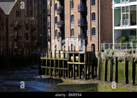 River Thames creek at low tide, converted Victorian warehouses originally used in the spice, tobacco and commodity trades Stock Photo