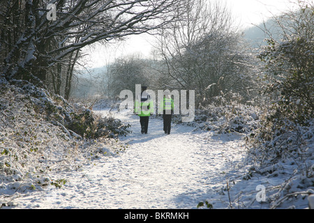 Two community police officers walking along a snow covered path at Bathpool, Kidsgrove, Stoke-on-Trent, Staffs Stock Photo