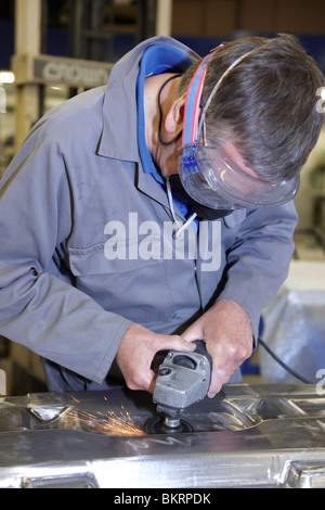factory floor worker using a angle grinder on metal surface Stock Photo