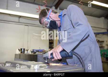 factory floor worker using a angle grinder on metal surface Stock Photo