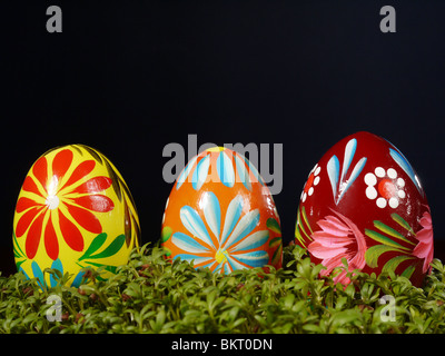 Three painted easter eggs in cress over black background Stock Photo