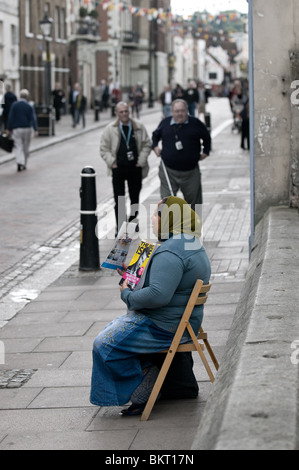 A woman sitting on a chair selling the Big Issue Stock Photo