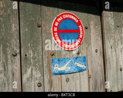 No Parking sign and Tow-away sign on old wood door. Stock Photo