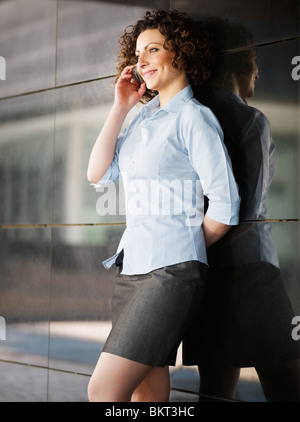 italian businesswoman talking on mobile phone outdoors and smiling. Vertical shape Stock Photo