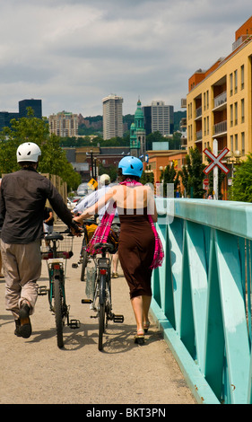 Cyclist walking on pedestrian bridge on Lachine Canal next to Atwater market Montreal canada Stock Photo