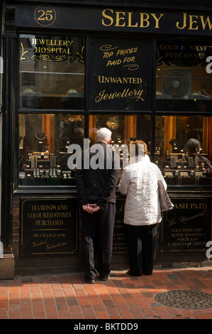 Two middle aged adult shoppers window shopping at a traditional jewellery  shop in the Lanes shopping area Brighton Sussex Stock Photo