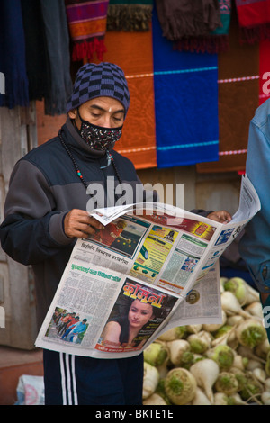 A NEPALI MAN reads a NEWSPAPER wearing a mask to help filter air pollution - KATHAMANDU, NEPAL Stock Photo