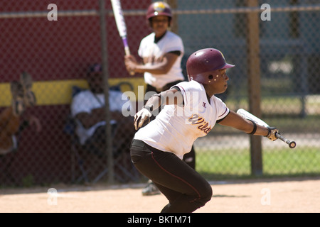 Softball player after hitting the ball, running to first base Stock Photo