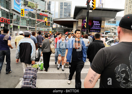 A group of pedestrians crossing the road at an intersection on the corner of Yonge and Dundas Streets, in downtown Toronto, Ontario, Canada. Stock Photo