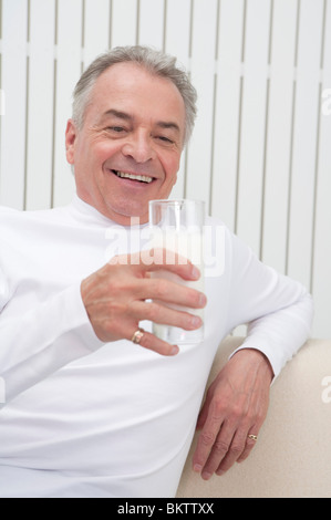 Domestic Life, a Senior-aged man holding a glass of drink and smiling Stock Photo