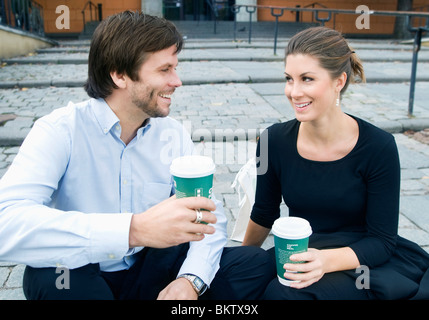 Man and woman sitting on stairs drinking coffee Stock Photo