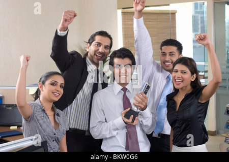Businessman and businesswoman cheering in office, smiling, portrait Stock Photo