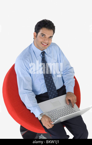 Young businessman using laptop, elevated view, portrait Stock Photo
