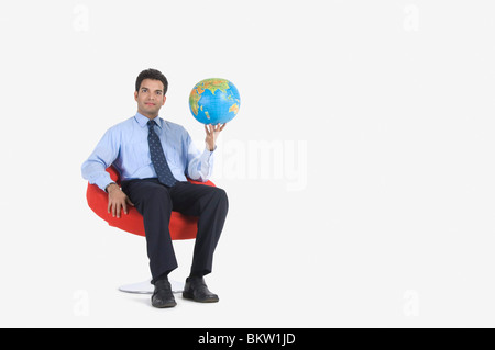 Young businessman holding world globe, portrait Stock Photo
