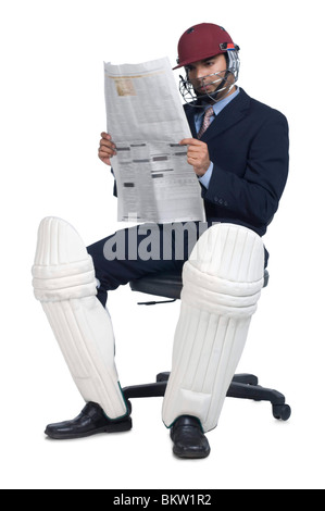Businessman wearing sports helmet, reading newspaper Stock Photo