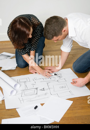 Two people looking at blueprints on floor Stock Photo