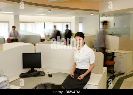 Businesswoman sitting on her table while colleagues  working on the background Stock Photo