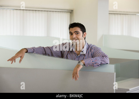 Businessman standing by the cubicle, smiling Stock Photo