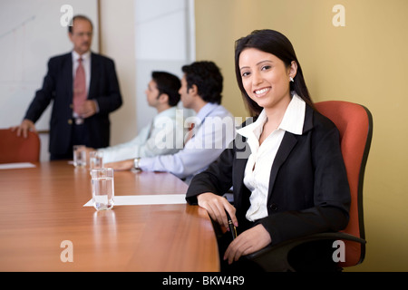 Businesswoman smiling at the camera, background businessmen talking Stock Photo