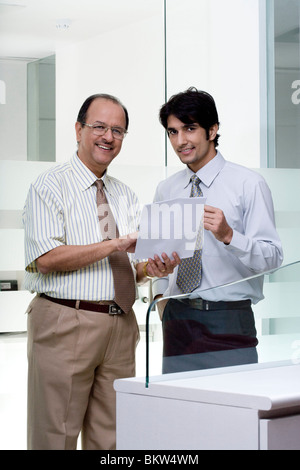Two businessman holding a document, smiling at the camera Stock Photo