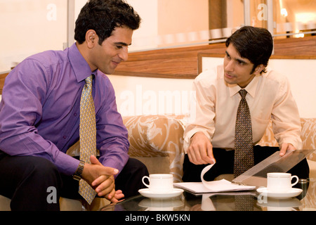 Two young businessman sitting on a couch, talking Stock Photo