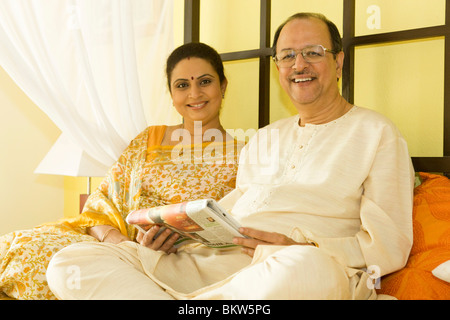 Senior couple reading newspaper together in bed Stock Photo