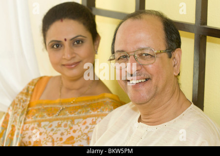 Senior couple sitting on bed, smiling Stock Photo