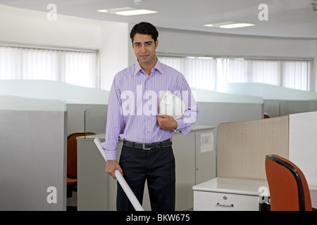 Male architect holding helmet and blueprint in the office, standing Stock Photo