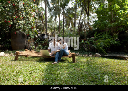 Couple with laptop sitting in the garden Stock Photo
