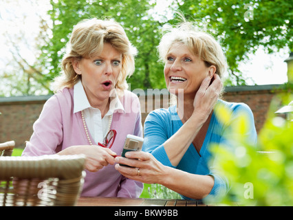 Two happy female friends sitting by table Stock Photo