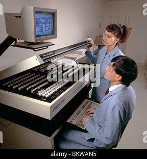 Male & female technicians using a liquid scintillation analyzer in the laboratory of an environmental engineering company. Stock Photo